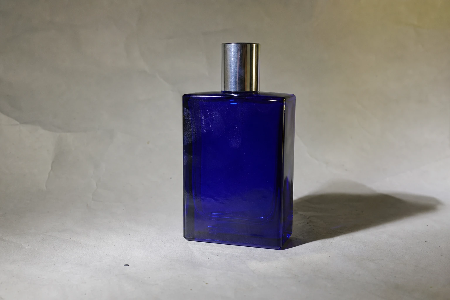 Flacon bleu avant nettoyage, sur un fond irrégulier avec poussières